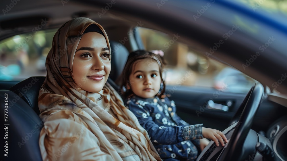 A Muslim woman in a hijab and a child are sitting in a car. The woman is smiling and the child is looking out the window