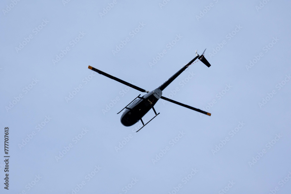 A black helicopter crosses the blue sky with clouds. Transportation. Urban. A black helicopter crosses the blue sky with clouds. Transportation. Urban.