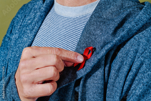 man pinning a red ribbon in his lapel