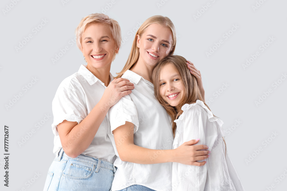 Little girl with her mom and grandmother hugging on light background Little girl with her mom and grandmother hugging on light background