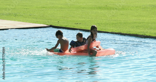 Children playing the swimming pool water on top of inflatable mattress © Marco