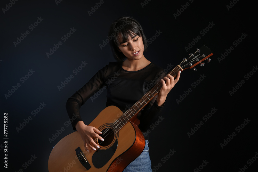 Cool young woman playing guitar on black background Cool young woman playing guitar on black background