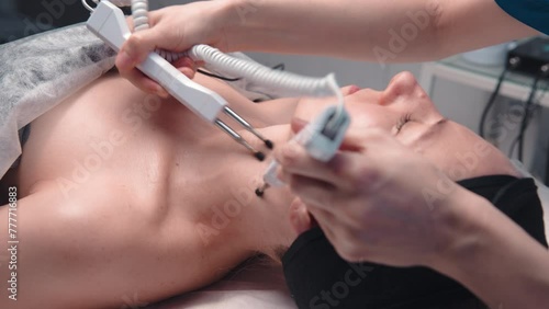 A middle-aged woman undergoes electrotherapeutic facial rejuvenation procedures in a cosmetologist's office. photo