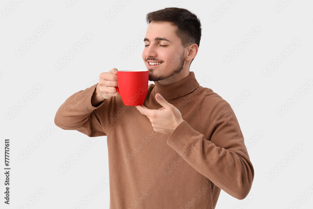 Young man with cup of tea on white background Young man with cup of tea on white background