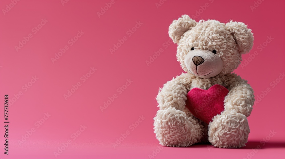 Plush bear holding red heart against pink background Plush bear holding red heart against pink background