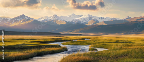 Landscape of beautiful summer blooming field in the valley with the river and snow mountains background at sunset 