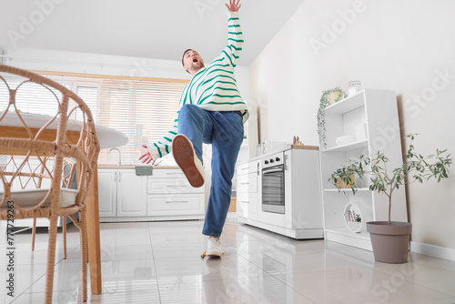 Young man falling after slipping on banana peel in kitchen