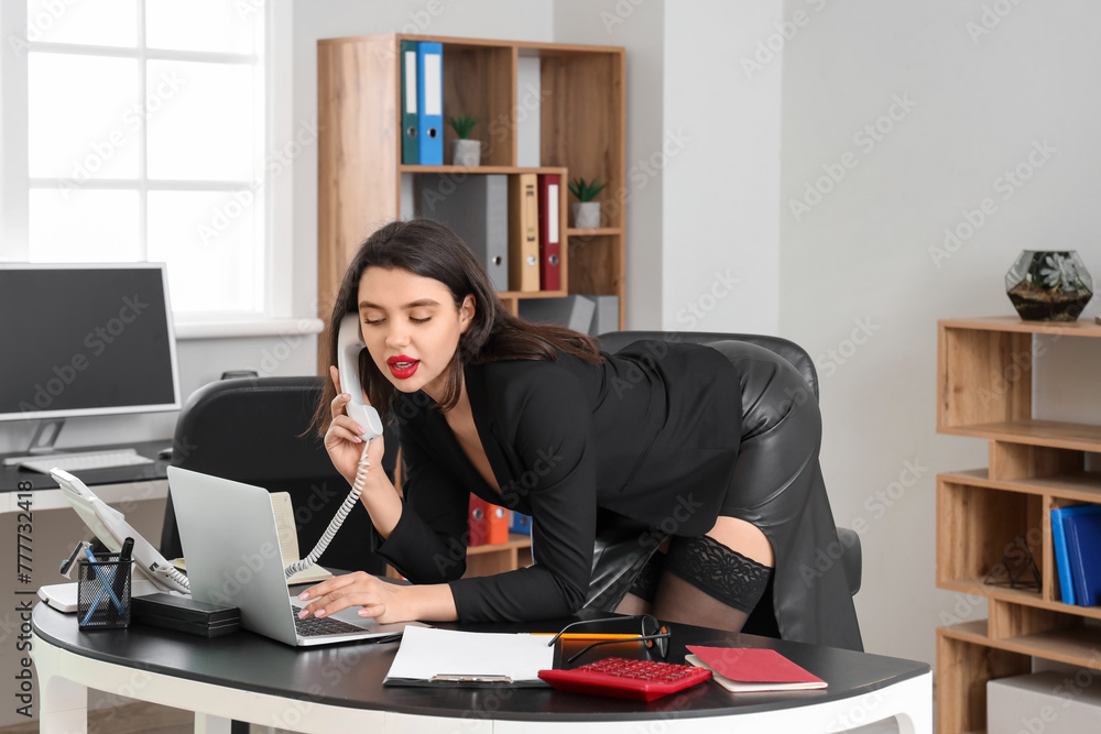 Attractive secretary talking by telephone in office Attractive secretary talking by telephone in office