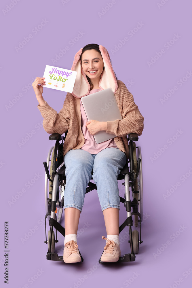Happy female freelancer in wheelchair with Easter greeting card and laptop on purple background
