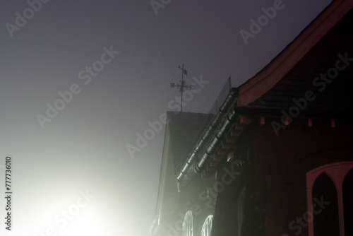 A weather vane on top of a building at night photo