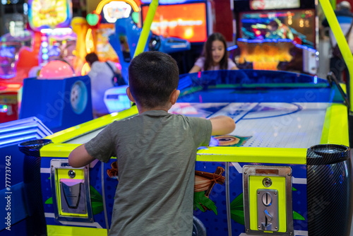 Energetic Play. Young Kids Enjoy Air Hockey Thrills at the Arcade Park photo