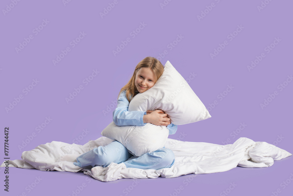 Adorable girl hugging pillow on white bed against lilac background Adorable girl hugging pillow on white bed against lilac background