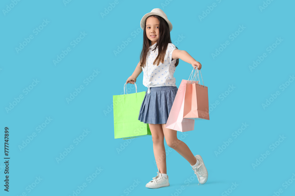 Portrait of fashionable little girl with shopping bags on blue background