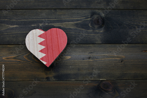 wooden heart with national flag of bahrain on the wooden background.
