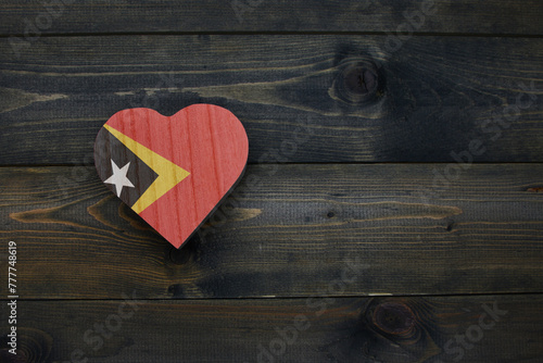 wooden heart with national flag of east timor on the wooden background. photo