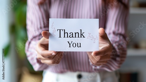 Person holding card that reads "Thank You" with both hands, close-up, no face shown