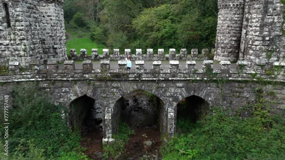 A woman walks across the medieval bridge in Lismore 4k A woman walks across the medieval bridge in Lismore 4k