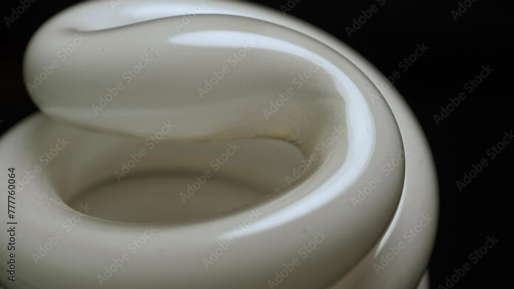 Fluorescent lamp lights close up macro view. Spiral tube bulb rotation on black background. Electric energy saving light bulb. Fluorescent lamp lights close up macro view. Spiral tube bulb rotation on black background. Electric energy saving light bulb.