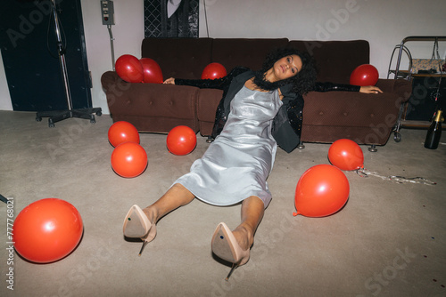 Elegant Woman Seated on Floor by Sofa with Red Balloons photo