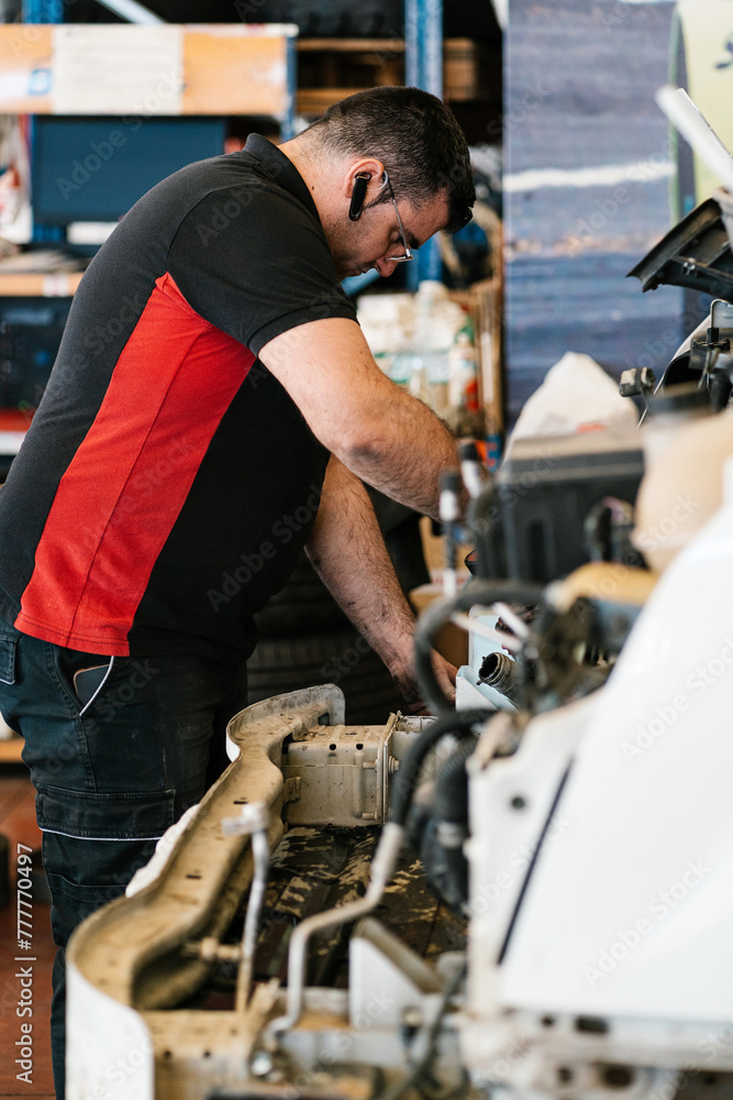 Male mechanic repairing engine in garage Male mechanic repairing engine in garage