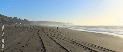 Person walking in the distance on Sand beach during windy summer day on pacific ocean  Iloca  Chile 