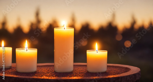 A table with three white candles on it, surrounded by trees in the background.
