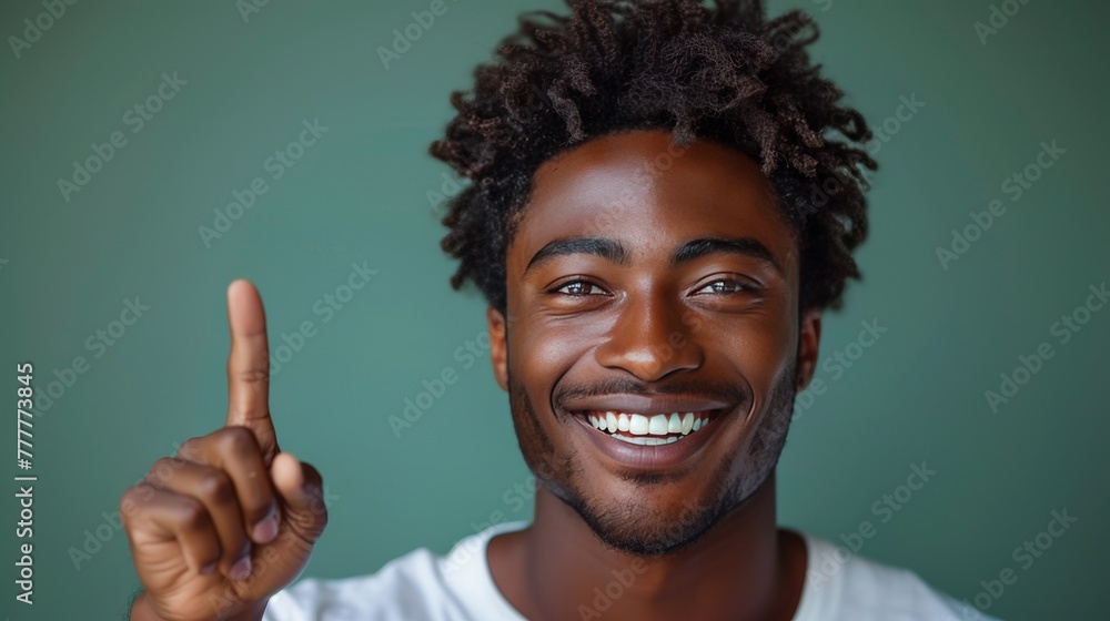 A handsome man with a big smile showing teeth, pointing his finger at an empty space, with a green background. A handsome man with a big smile showing teeth, pointing his finger at an empty space, with a green background.
