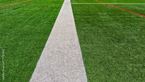 Football Field Turf. Bright green turf football field surface with white sidelines and yard line markings. Overhead view.