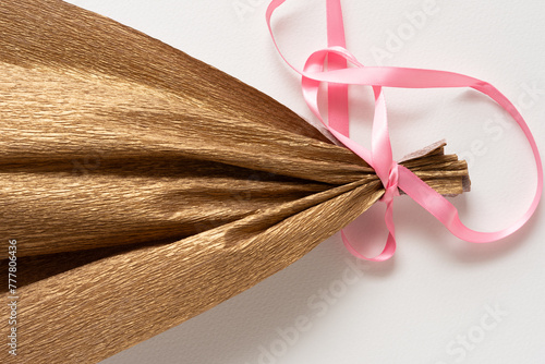 crepe paper fan with pink ribbon on blank paper