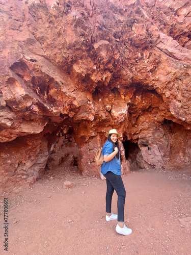 Latin adult woman geologist with hat explores and investigates opal mine, studies the minerals and analyzes the red land