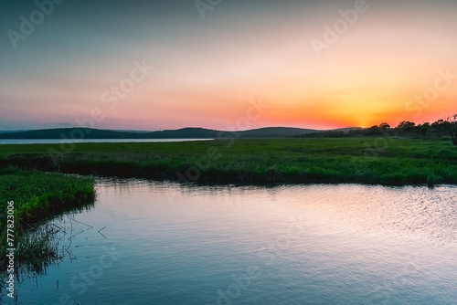 A small picturesque river among a green meadow during sunset. Small river in the countryside. Feeling of freedom, happiness, nostalgia. Tavrichanka, Primorsky Krai, Russia