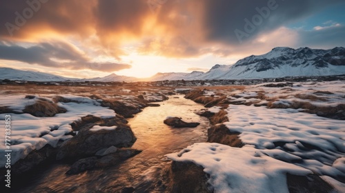 Wide angle majestic view of rocky mountains covered with snow near frozen lake under cloudy sunset sky