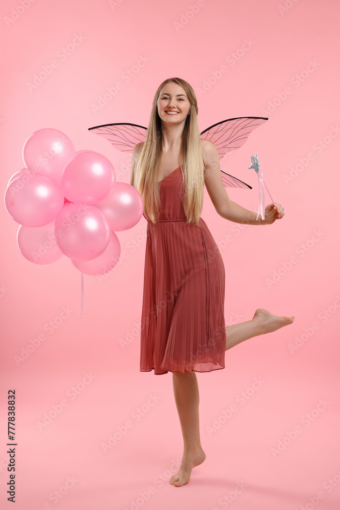 Beautiful girl in fairy costume with wings, magic wand and balloons on pink background Beautiful girl in fairy costume with wings, magic wand and balloons on pink background