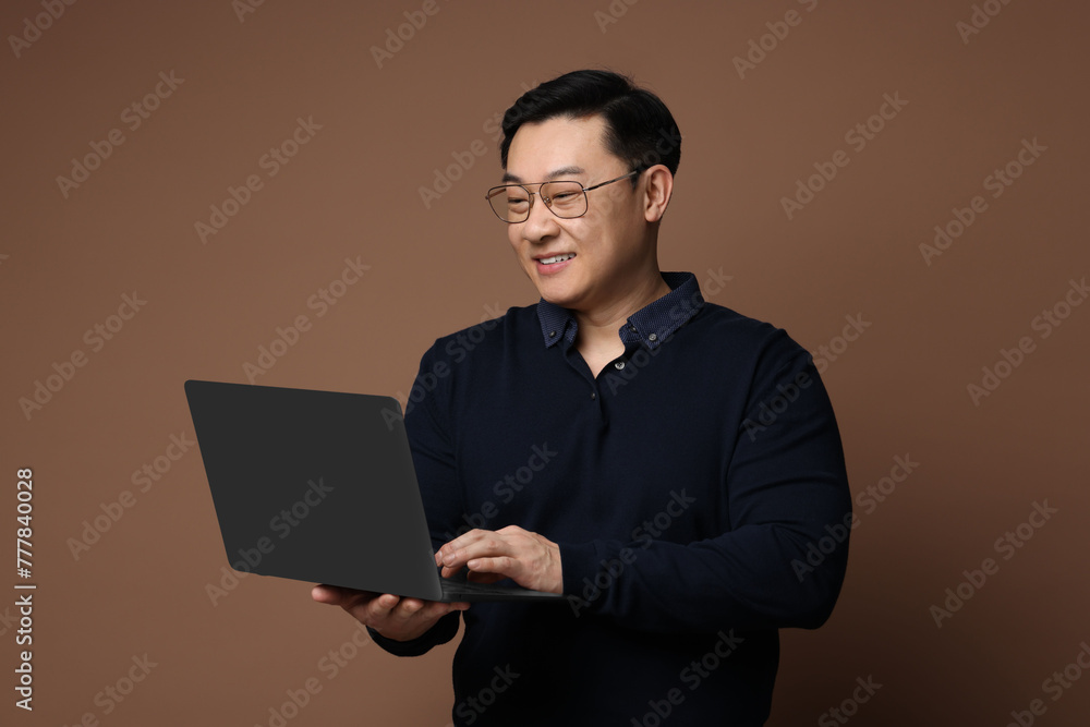 Portrait of happy man with laptop on brown background