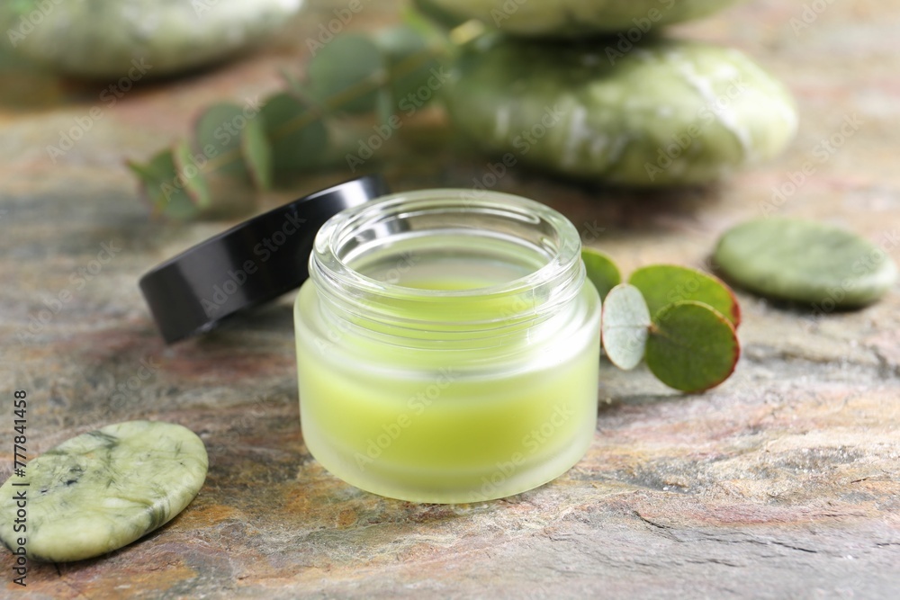 Jar of cream, spa stone and eucalyptus leaves on textured table, closeup. Body care product Jar of cream, spa stone and eucalyptus leaves on textured table, closeup. Body care product