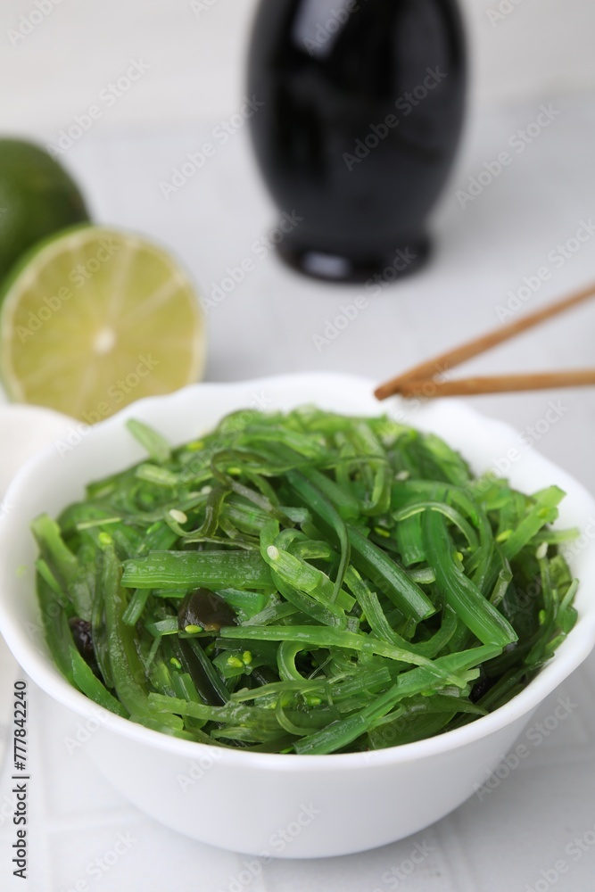 Tasty seaweed salad in bowl on white tiled table, closeup Tasty seaweed salad in bowl on white tiled table, closeup