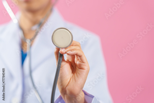 medical doctor close up shot holding stethoscope isolated on pink background.