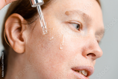 A woman applies lotion to her face photo