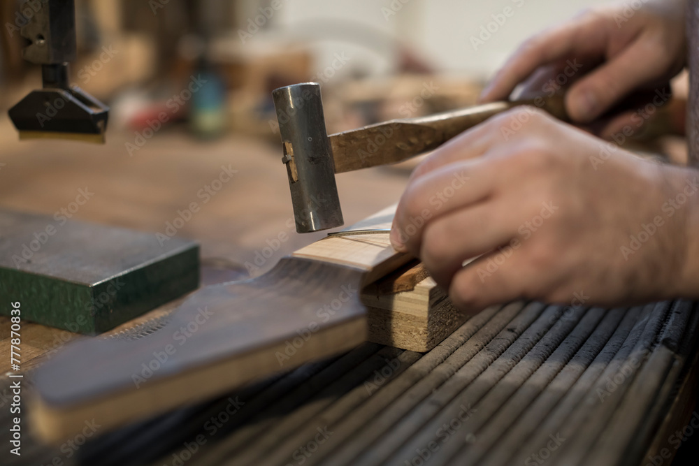 Luthier puts the frets on the guitar neck Luthier puts the frets on the guitar neck