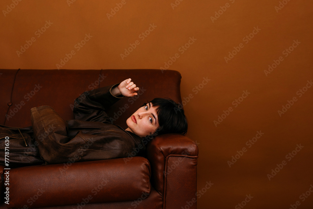 Stylish young lady lying on leather sofa in living room Stylish young lady lying on leather sofa in living room