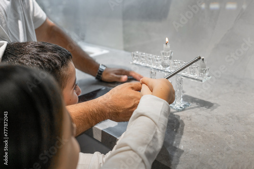 Family Hanukkah Celebration. Father and Children Light Hanukkah Candle photo