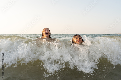 A brother and sister trying to take a wave at the beach