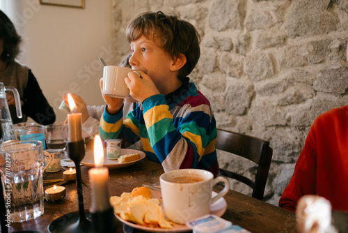kid having hot drink during family breakfast/brunch photo