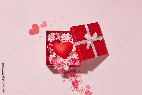 Paper art flowers in open gift box on pink background with red heart