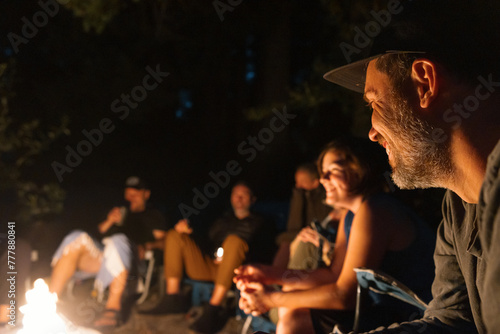 Man smiling around campfire with friends and family. photo
