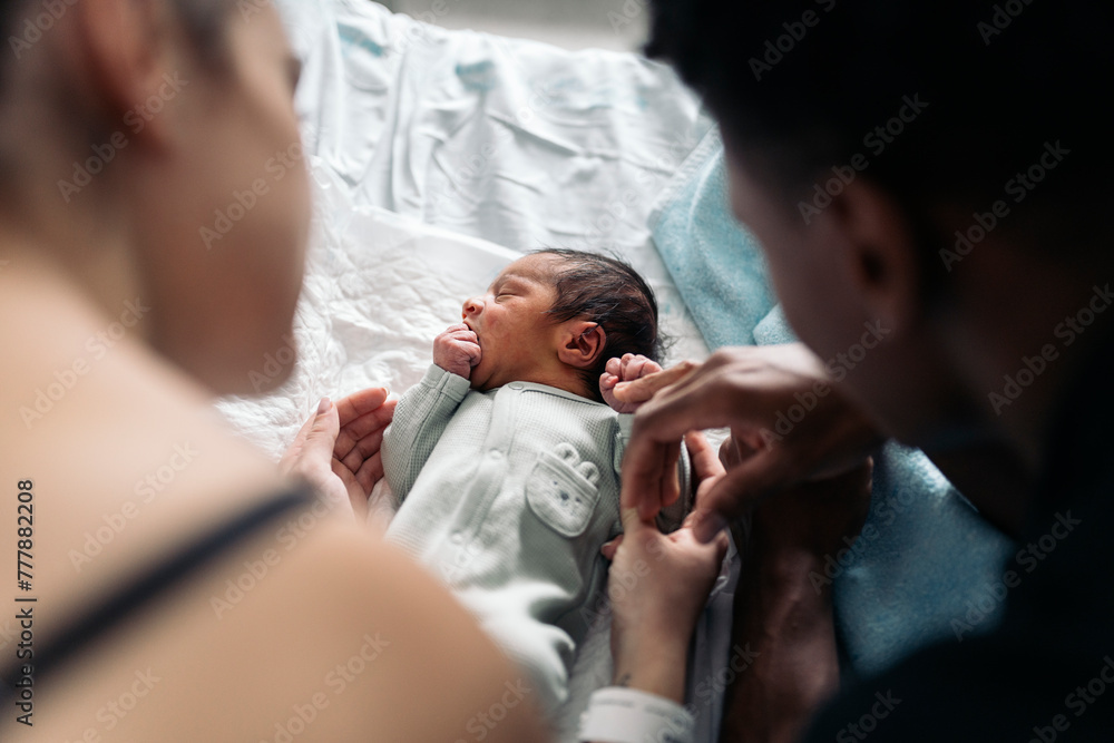 Diverse parents admiring baby after giving birth Diverse parents admiring baby after giving birth