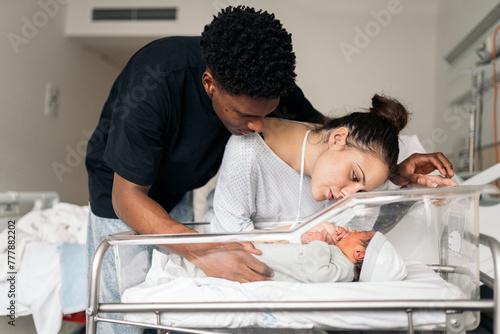 Diverse parents admiring baby after giving birth photo