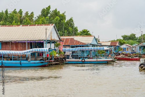 Colourful long boats next to houses floating on a river at Chau Doc in Vietnam