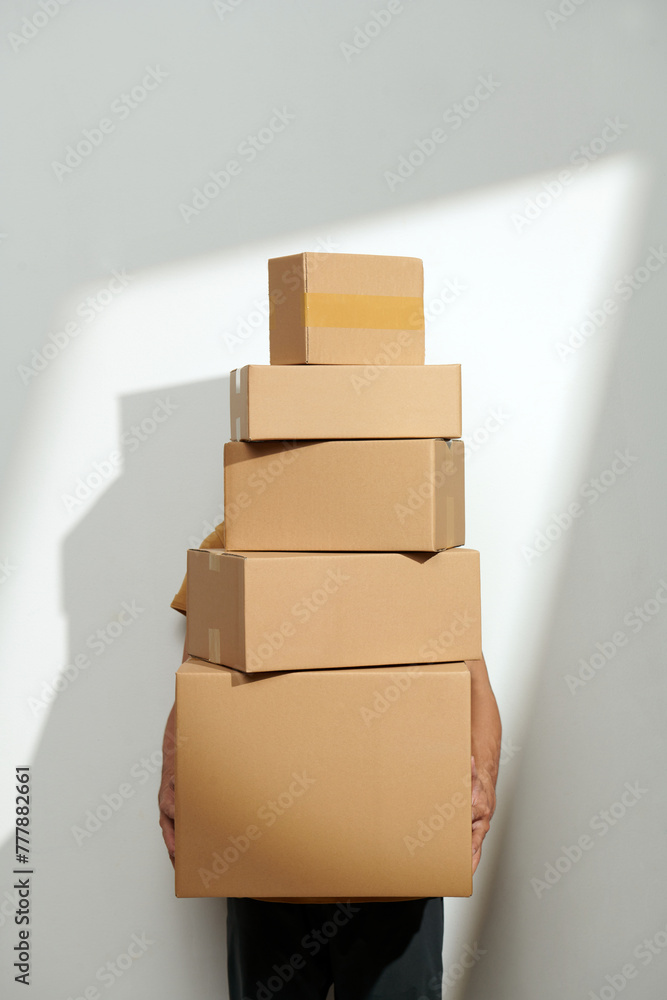© Marc Tran/Stocksy - Man with moving boxes on white wall with sunlight