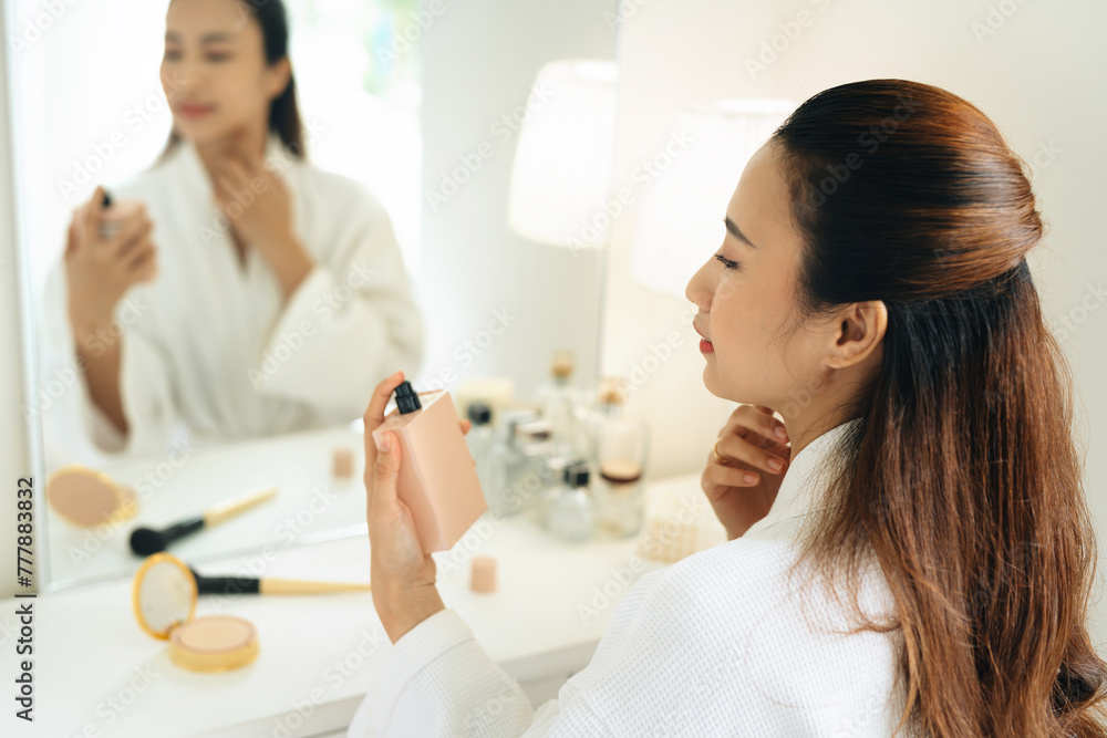 Beautiful young woman use perfume in a bedroom Beautiful young woman use perfume in a bedroom
